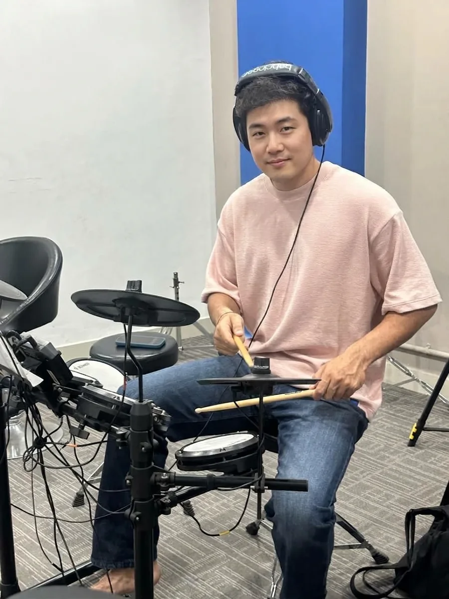 A student at an electronic drum kit with headphones on