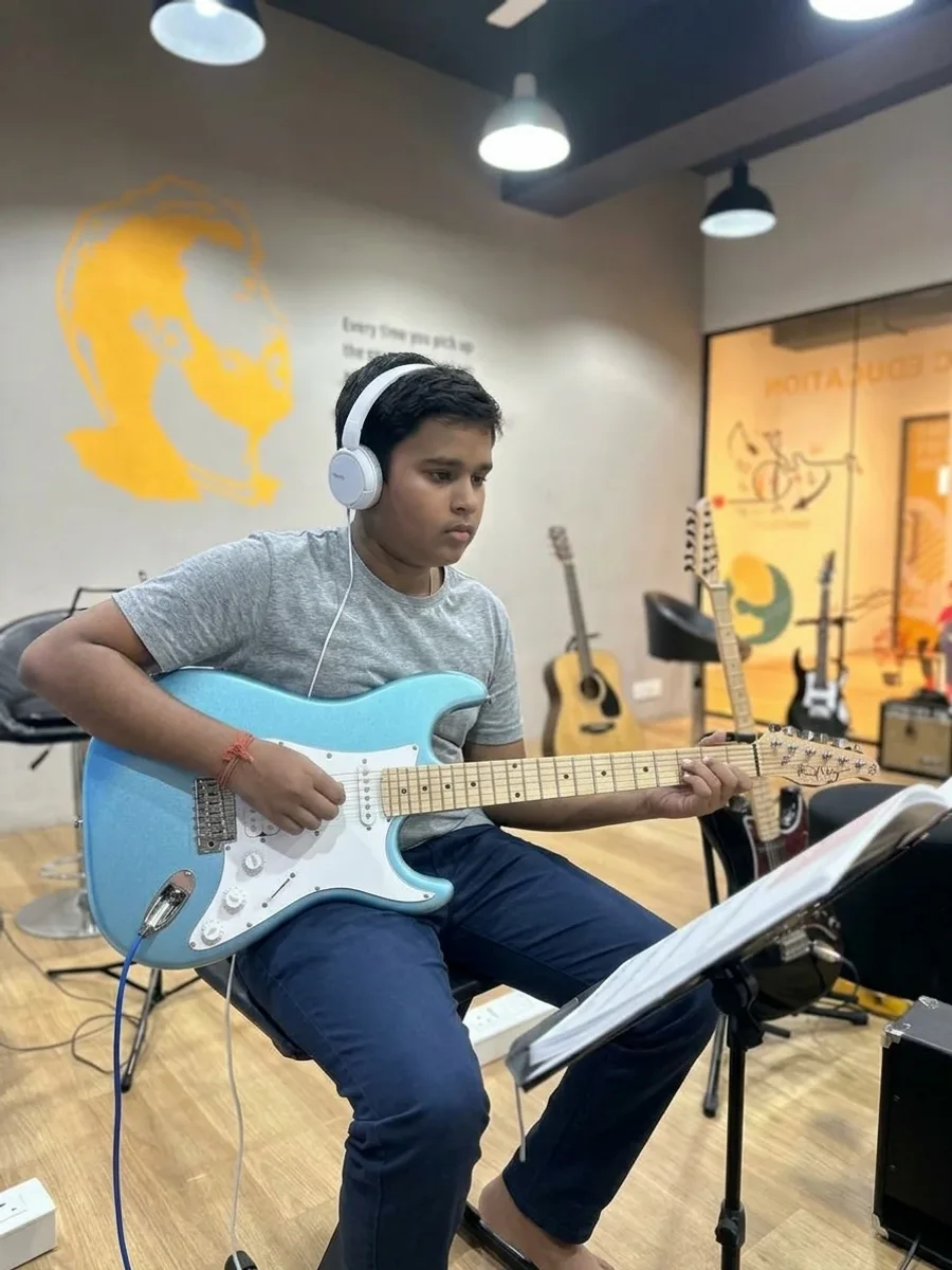 A student playing electric guitar, reading from a music stand