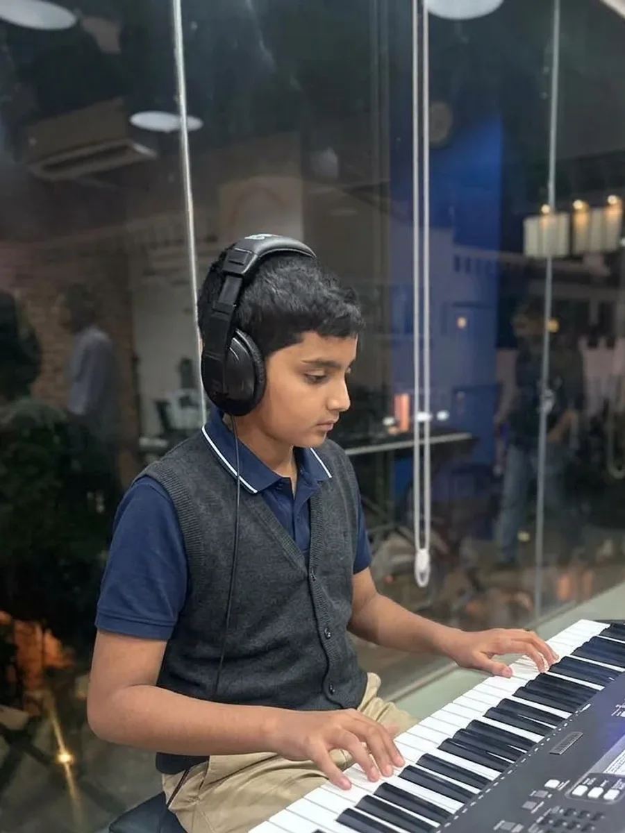 A student playing a keyboard with headphones on